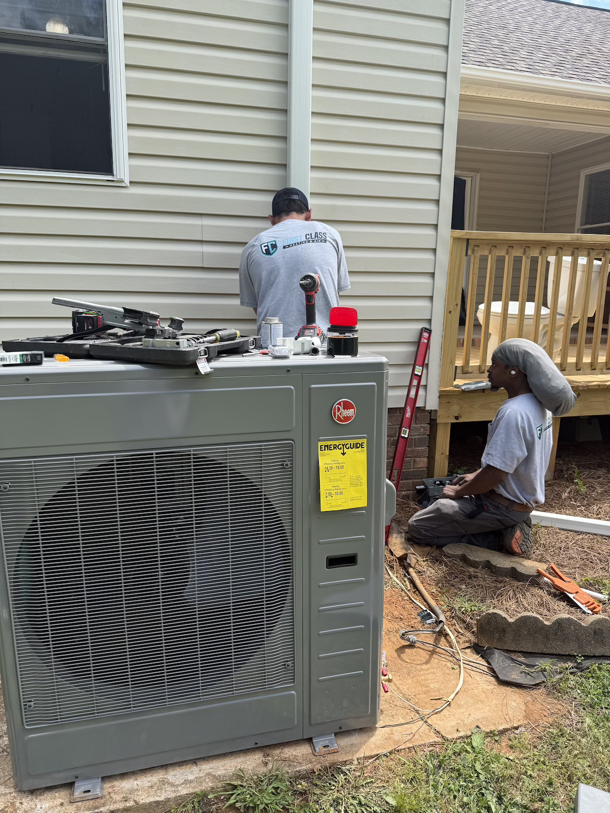 Two-man crew installing a Rheem condenser at residential home