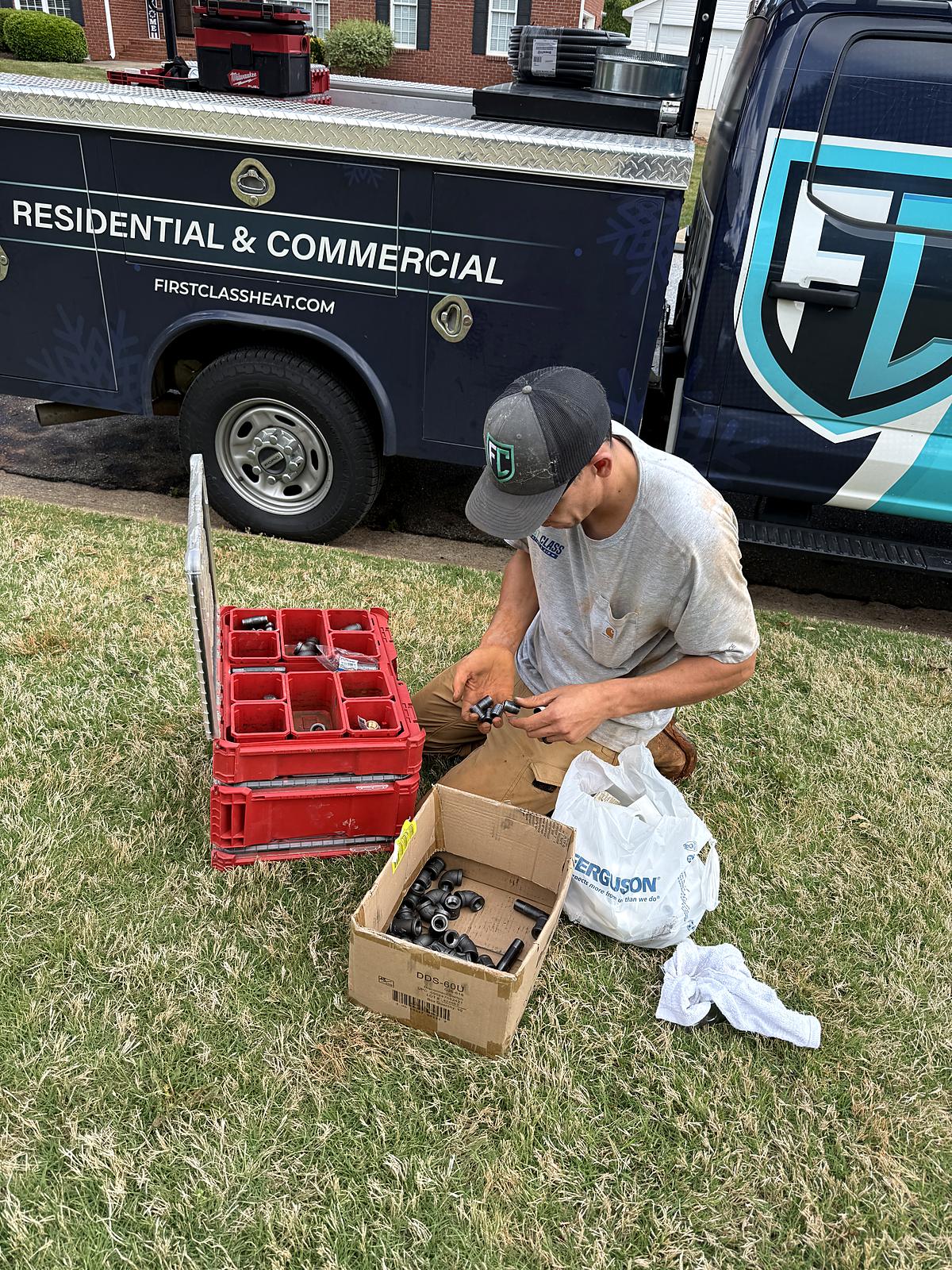 Cameron sorting gas pipe fittings from his Milwaukee Packout next to the First Class truck