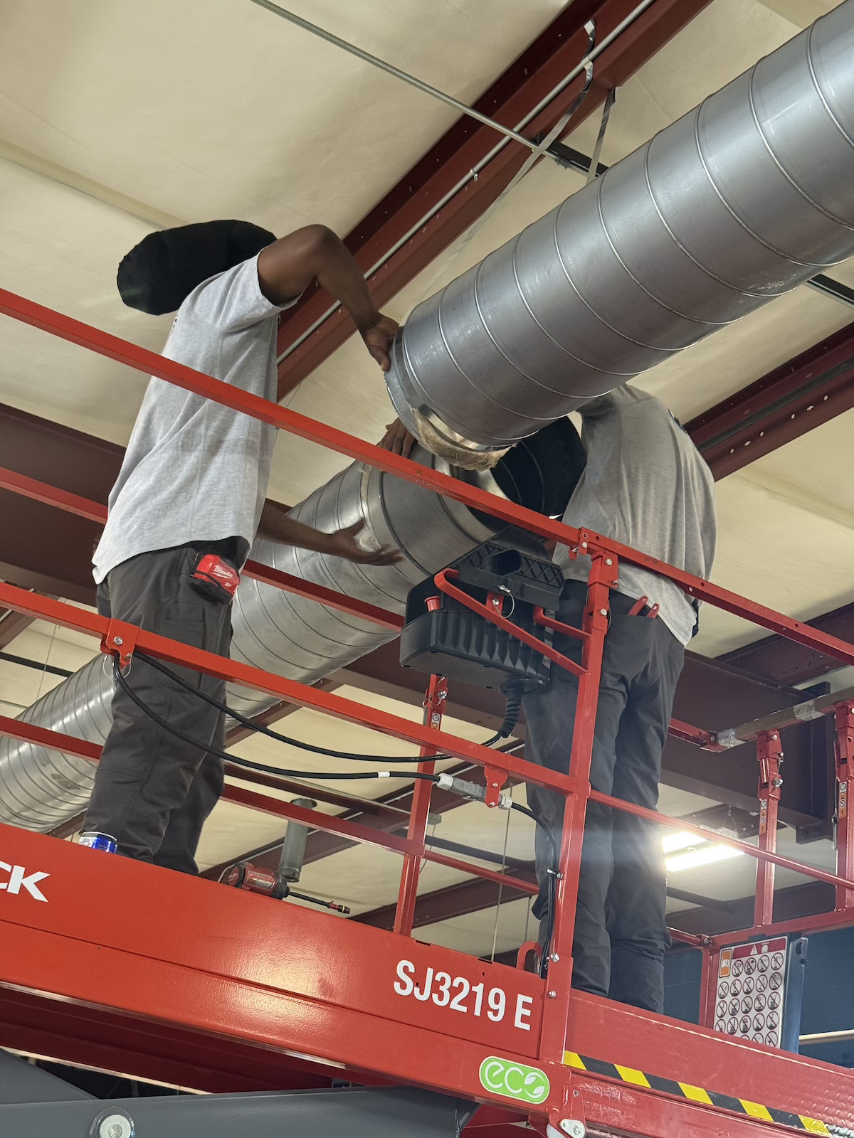 Commercial ductwork being installed in steel-frame building