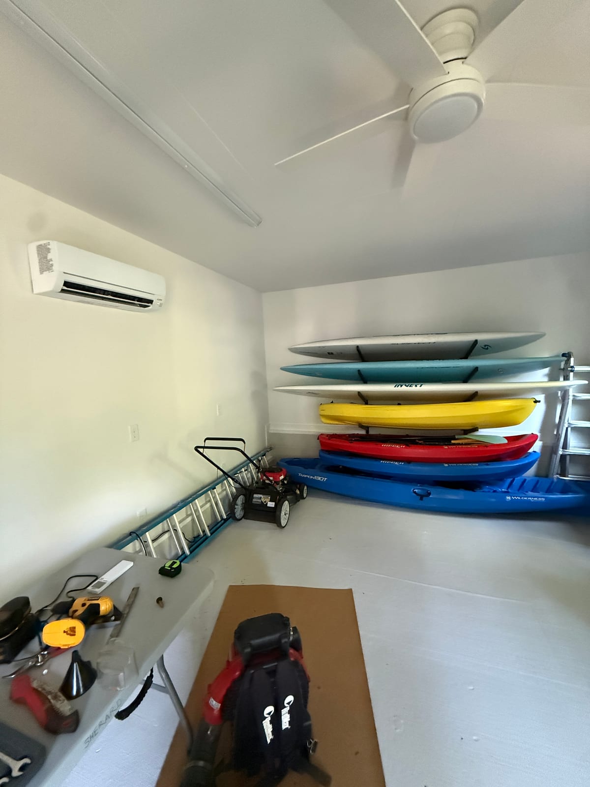 Ductless mini split indoor head cooling a garage storage room with kayaks and paddleboards