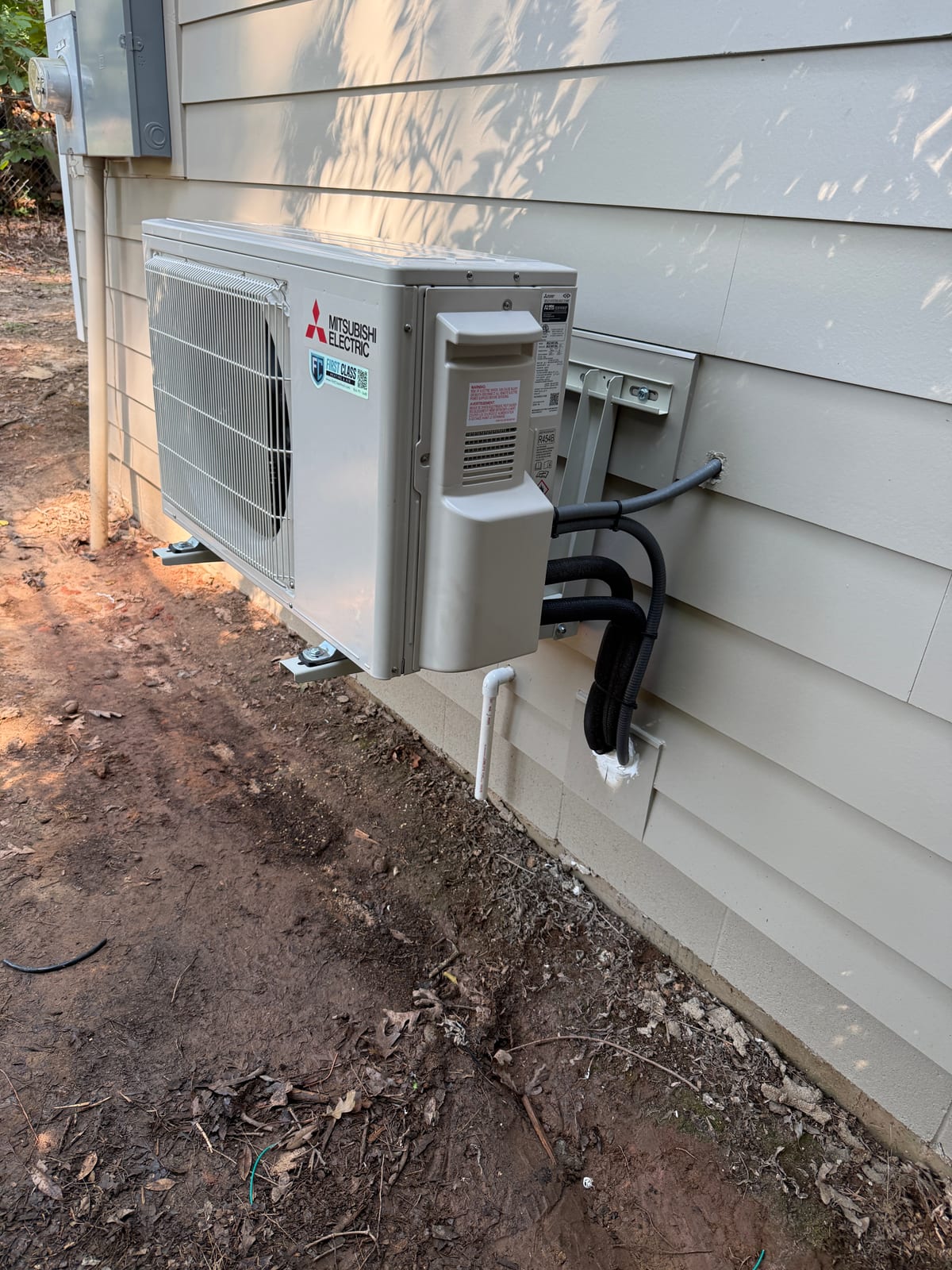 Mitsubishi Electric mini split outdoor unit with insulated line set covers and electrical disconnect neatly run down the wall