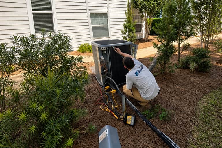 First Class Heating & Air technician servicing an outdoor AC condenser unit during AC maintenance in Greenville, SC