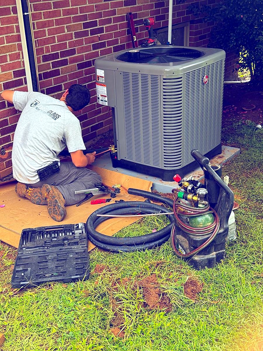 Cameron brazing copper lines on a new Rheem condenser during an AC replacement