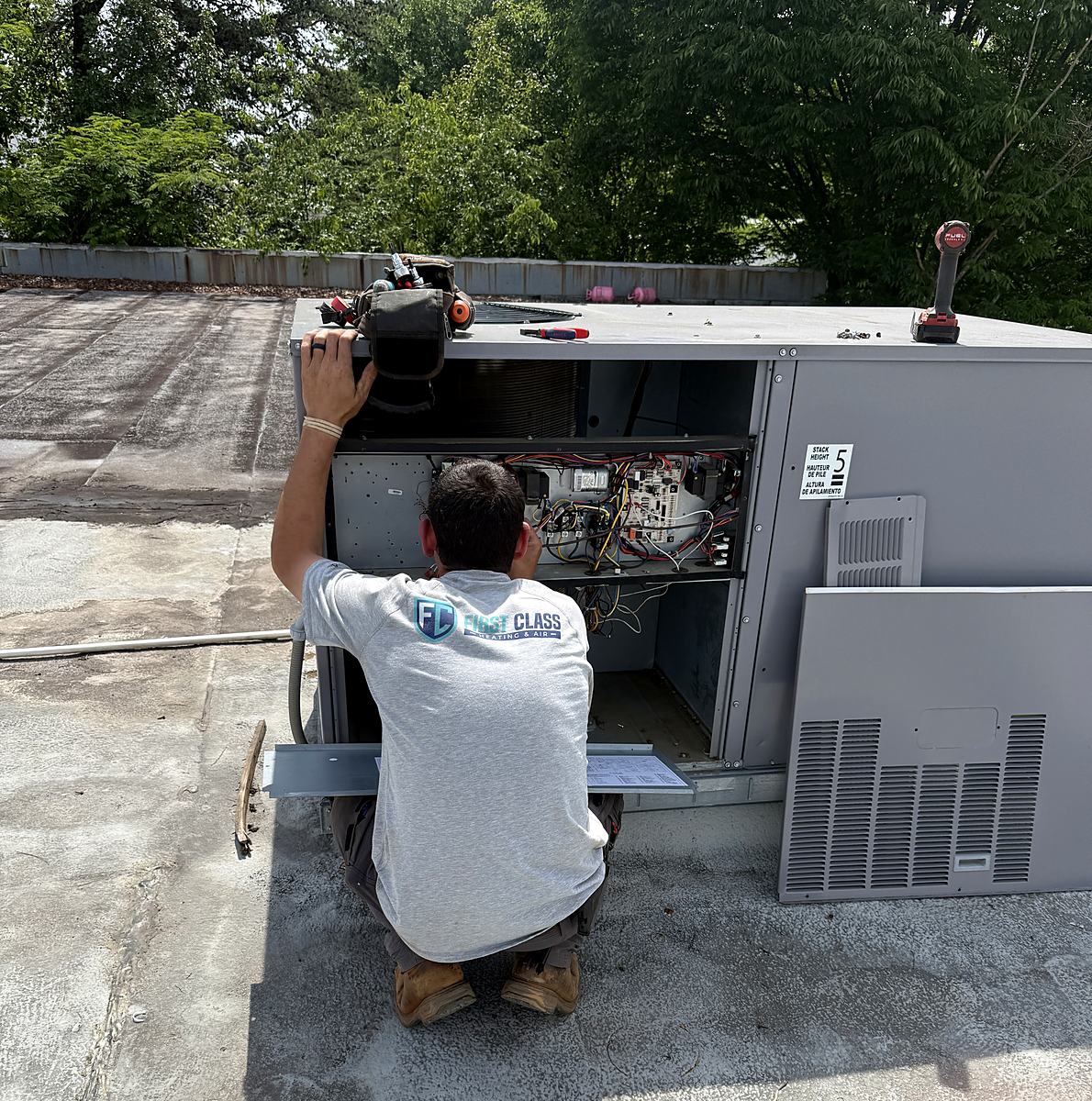 First Class Heating & Air technician repairing a commercial rooftop package unit on Haywood Ave in Greenville, SC