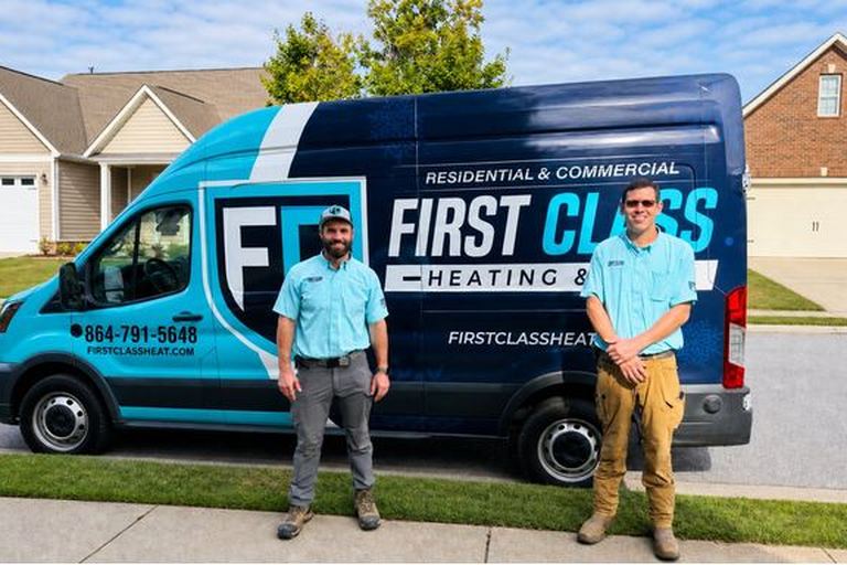 First Class Heating and Air technicians standing in front of the branded service van in a Greenville SC neighborhood
